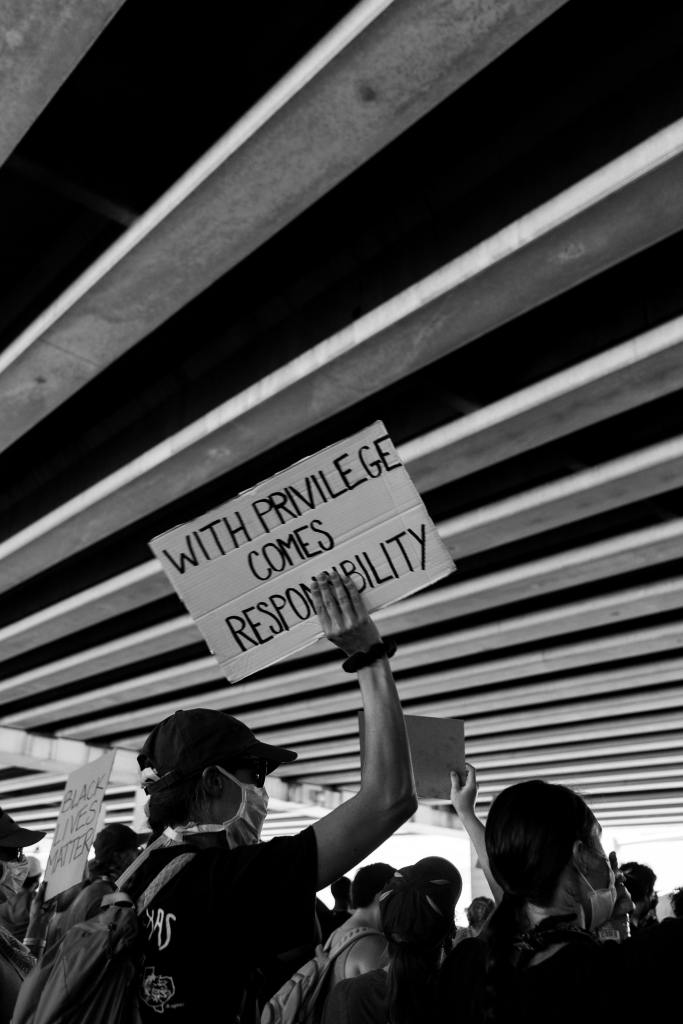 A protester holds a sign reading 'with privilege comes responsibility'